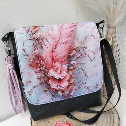 Black and white canvas shoulder bag with pink floral and feather design, displayed on a shelf